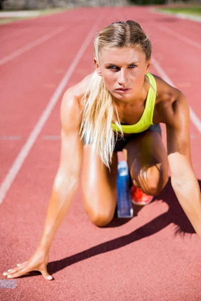 Atleta feminina pronta para correr em pista de corrida — Fotografia de Stock
