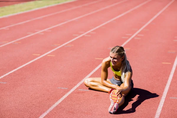 Atleta feminina aquecendo na pista de corrida — Fotografia de Stock