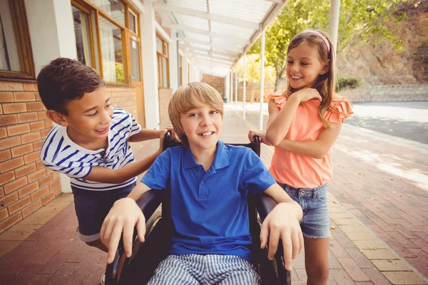 Школьники разговаривают с мальчиком на инвалидной коляске — стоковое фото