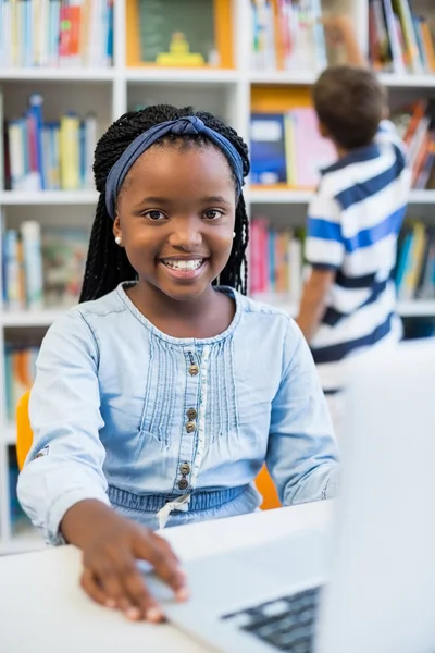 Écolière utilisant un ordinateur portable dans la bibliothèque — Photo
