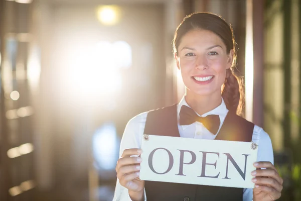 Smiling waitress holding open sign — Stock Photo, Image