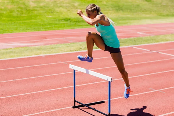 Kvinnelig friidrettsutøver som hopper over hekken – stockfoto