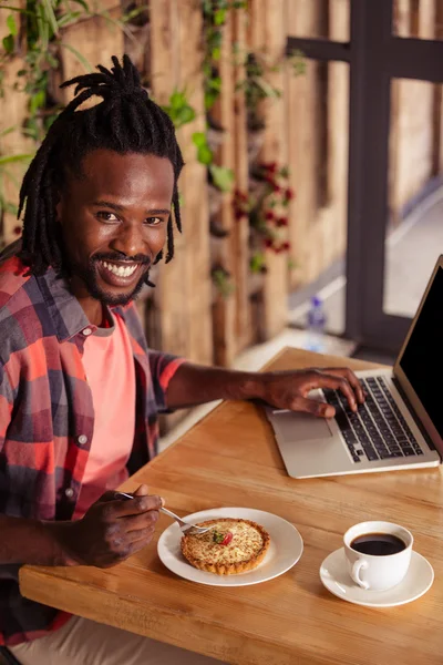 Hipster hombre con pastelería y portátil — Foto de Stock