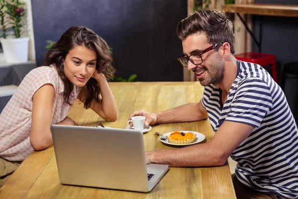 Couple using laptop in cafeteria — Stock Photo, Image