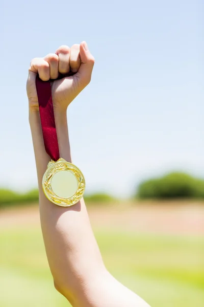 Hand of female athlete holding gold medal — Stock Photo, Image