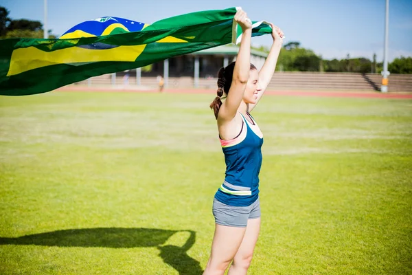 Atleta feminina segurando uma bandeira brasileira — Fotografia de Stock