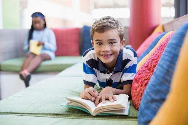 Studente sdraiato sul divano e libro di lettura — Foto Stock