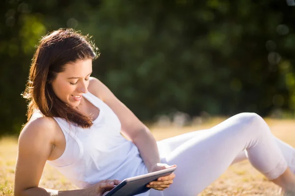 Kvinna sitter på gräset och använder digital tablet — Stockfoto