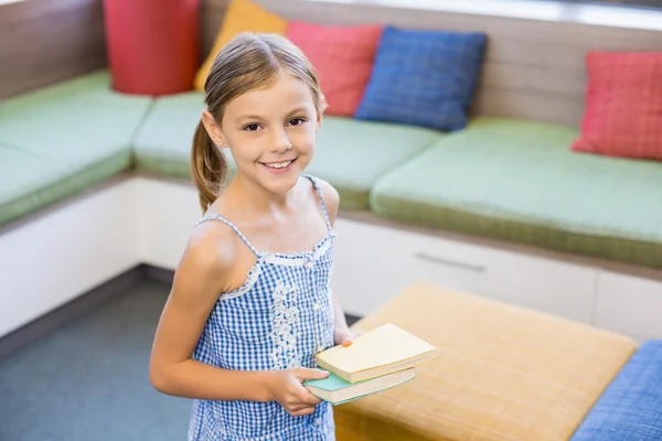 Κορίτσι που κρατά ένα βιβλίο στη βιβλιοθήκη — Φωτογραφία Αρχείου