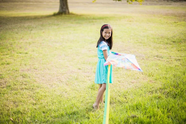 Sorridente ragazza che gioca con aquilone nel parco — Foto Stock