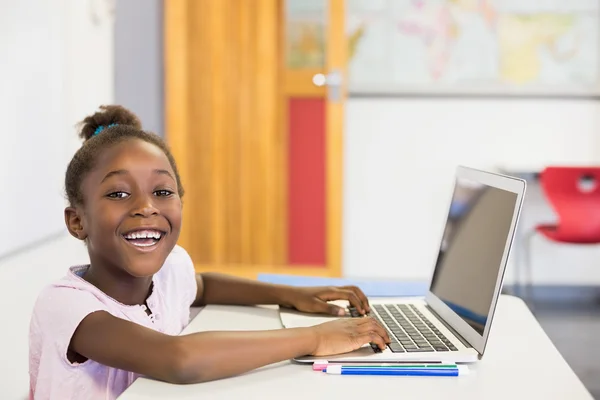 Schoolgirl using laptop in classroom — Stock Photo, Image