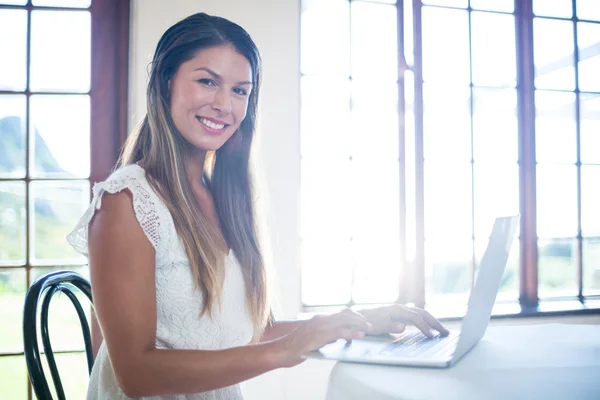 Smiling woman using laptop in restaurant — Stock Photo, Image