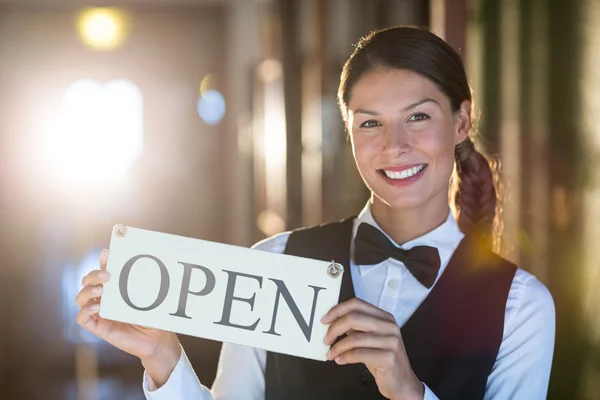 Smiling waitress holding open sign — Stock Photo, Image