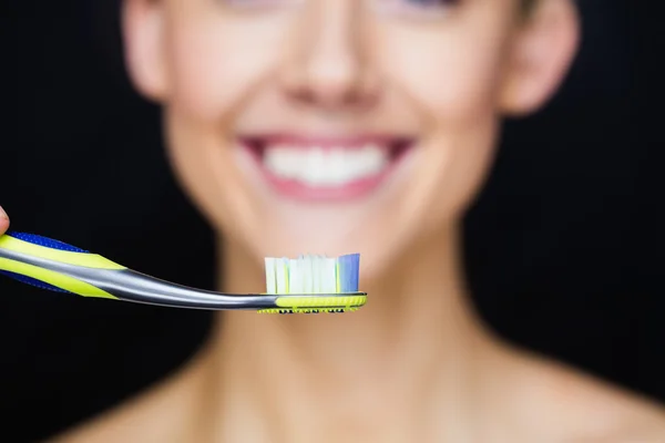 Céntrate en el cepillo de dientes con la sonrisa de la mujer — Foto de Stock