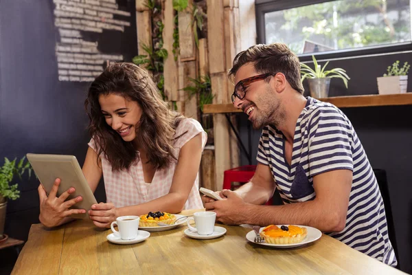 Casal usando comprimido na cafetaria — Fotografia de Stock