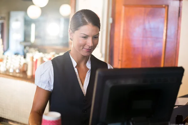 Kellnerin arbeitet am Computer am Tresen — Stockfoto