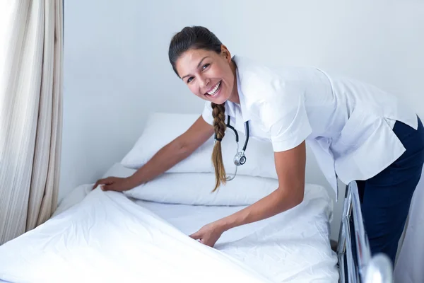 Femme médecin souriante préparant le lit — Photo