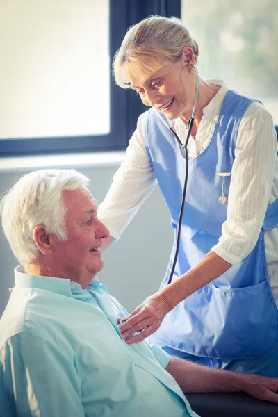 Женщина-врач проверяет сердцебиение пожилого мужчины — стоковое фото