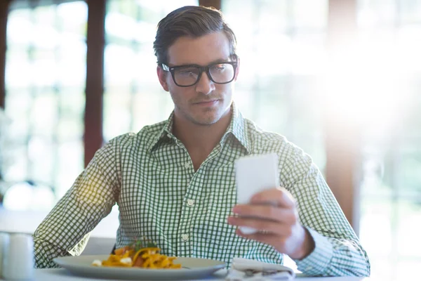 Man met behulp van de telefoon terwijl het hebben van lunch — Stockfoto