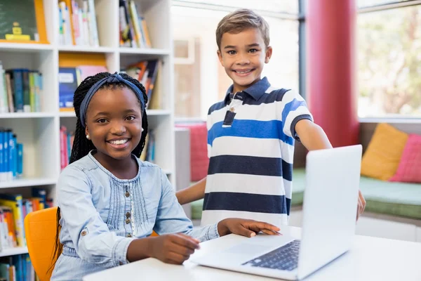 Mosolygó iskolás gyerekek használ egy laptop — Stock Fotó