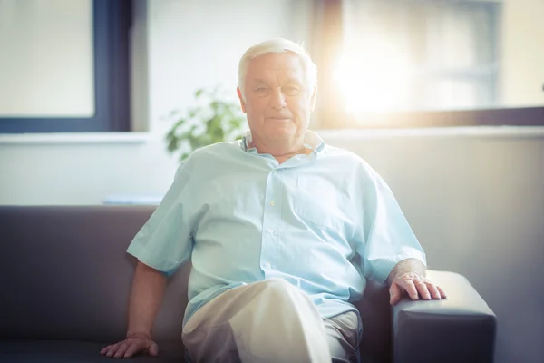 Portret szczęśliwy starszy mężczyzna siedzi na kanapie — Zdjęcie stockowe