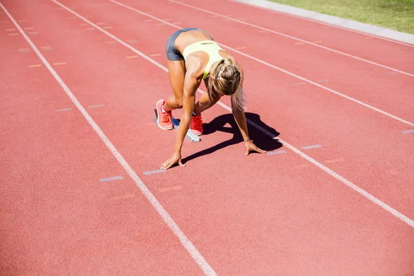 Atleta feminina pronta para correr em pista de corrida — Fotografia de Stock