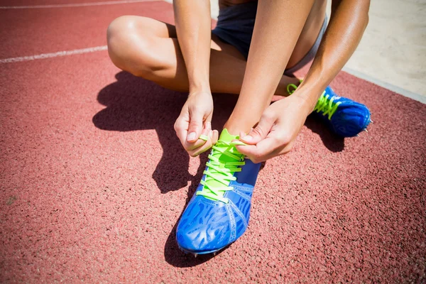 Atleta feminino amarrando seus sapatos de corrida — Fotografia de Stock