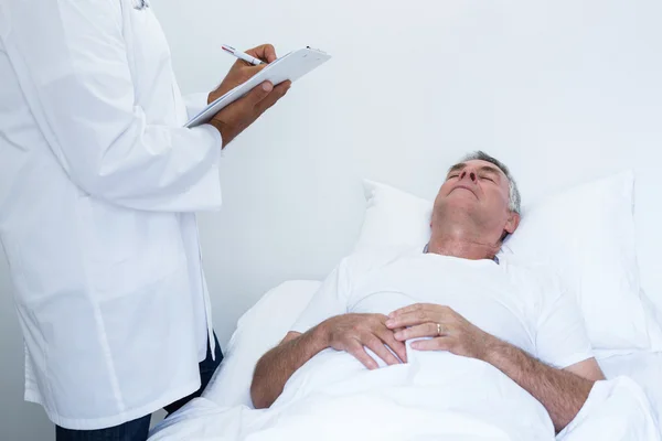 Male doctor writing medical report — Stock Photo, Image