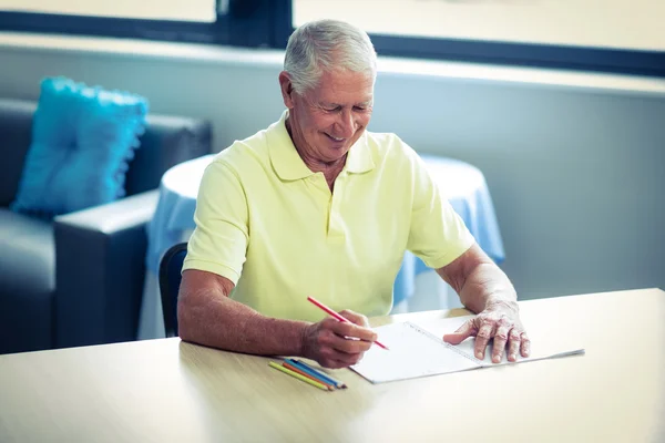 Hombre mayor dibujando con un lápiz de color en el libro de dibujo — Foto de Stock