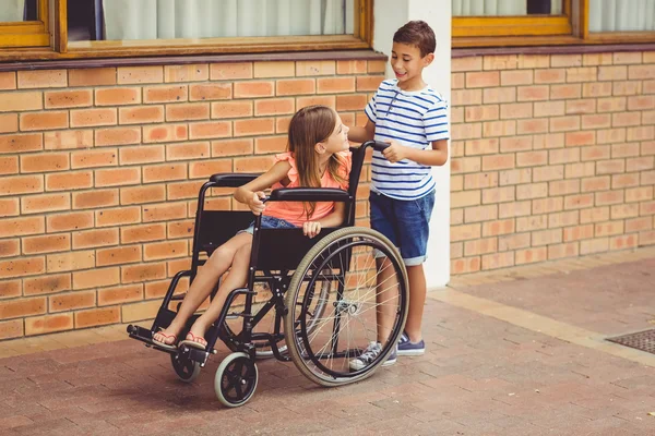 Estudante falando com menina em cadeira de rodas — Fotografia de Stock