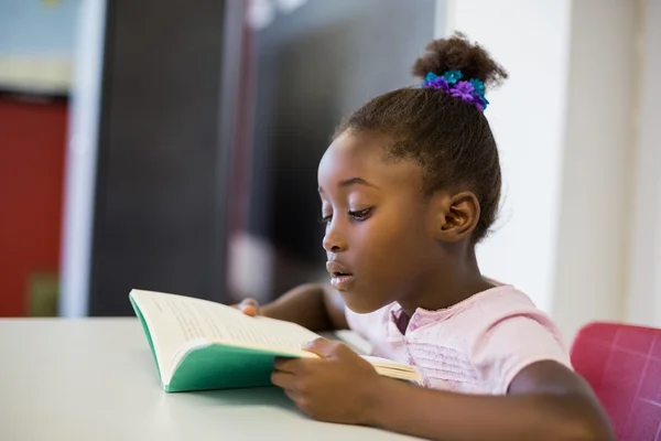 Escola menina leitura livro em sala de aula — Fotografia de Stock