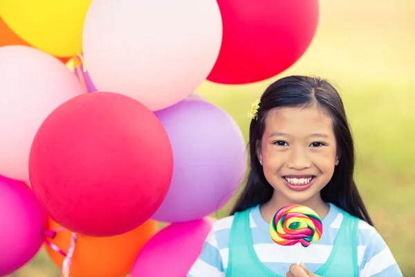 Chica sosteniendo globos y piruleta — Foto de Stock