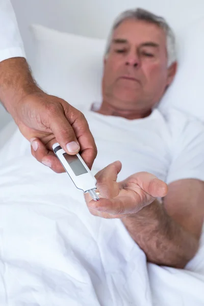 Médico masculino testando diabetes de homem idoso em medidor de glicose — Fotografia de Stock