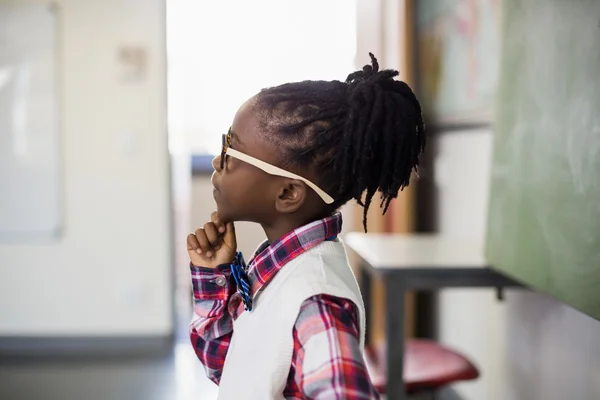 Tankeväckande skolflicka med hand på hakan — Stockfoto