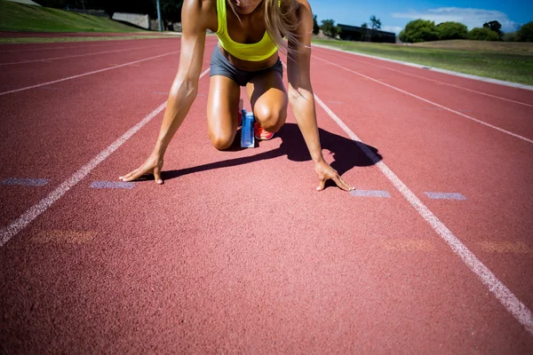 Atleta feminina pronta para correr em pista de corrida — Fotografia de Stock