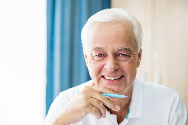 Sonriente anciano sosteniendo lápiz de color — Foto de Stock
