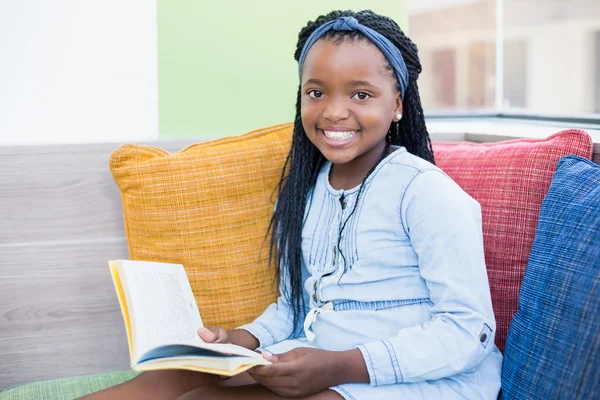 Schoolmeisje op de sofa en lezing boek — Stockfoto