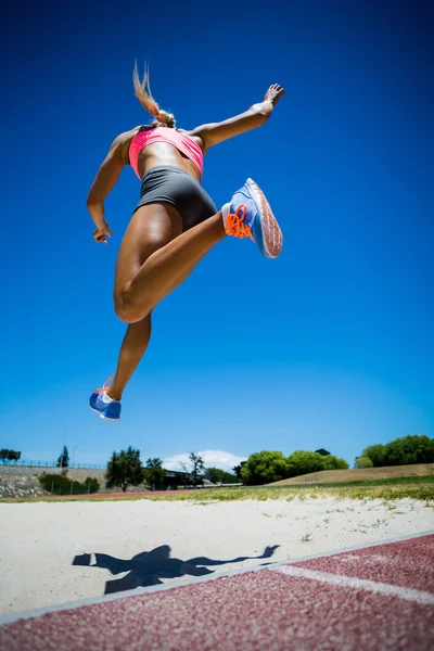 Kvinnelig friidrettsutøver med lengdehopp – stockfoto
