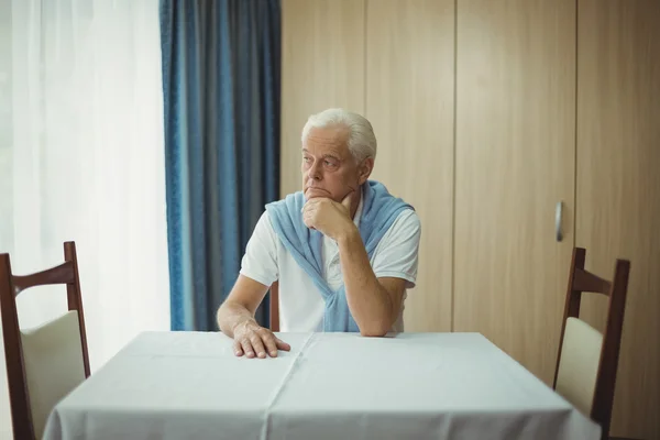 Uomo anziano seduto a un tavolo — Foto Stock