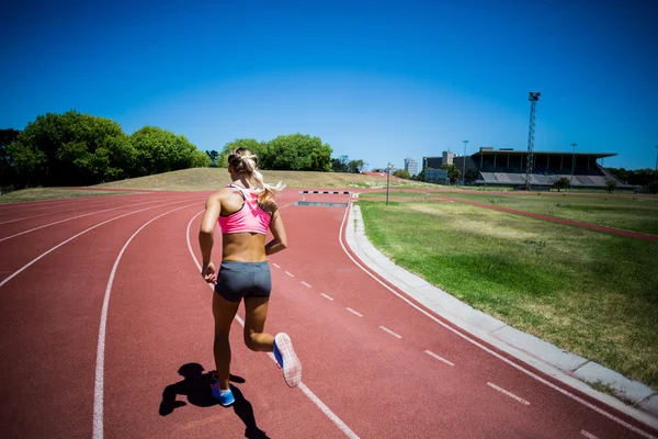 Visão traseira do atleta feminino correndo na pista de corrida — Fotografia de Stock
