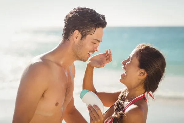 Mujer aplicando crema solar en la cara de los hombres — Foto de Stock