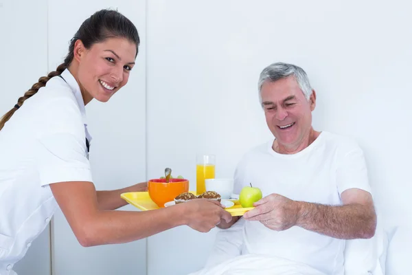 Medico donna che serve la colazione all'uomo anziano — Foto Stock