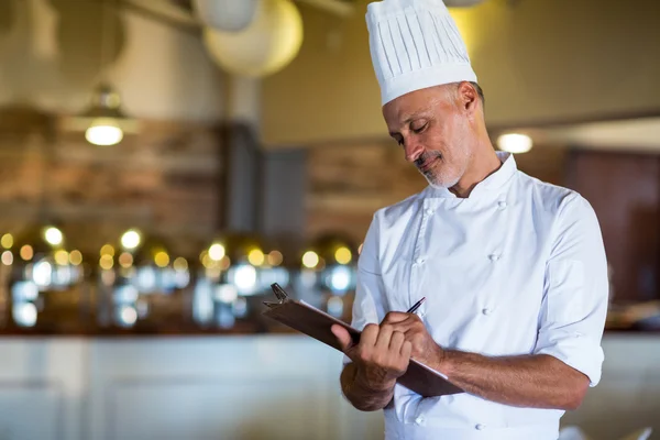 Chef escribiendo en un portapapeles — Foto de Stock