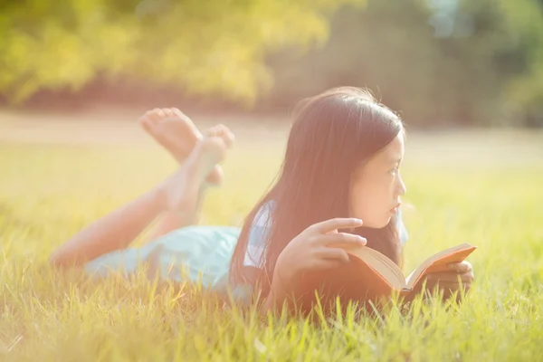Omtänksamt flicka på gräs läser bok — Stockfoto