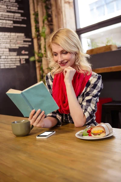 Woman reading novel in cafeteria — Stock Photo, Image