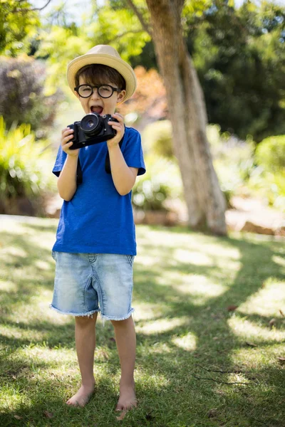 Мальчик в очках держит камеру — стоковое фото