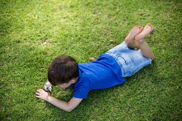 Boy examining grass with magnifying glass — Stock Photo, Image