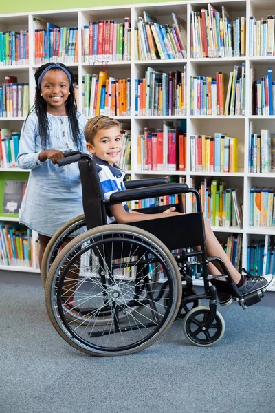 Schoolgirl with schoolboy on wheelchair — Stock Photo, Image