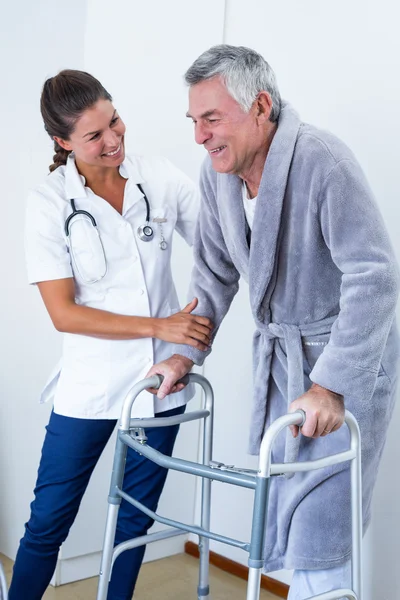 Doctor helping senior man to walk with walker — Stock Photo, Image