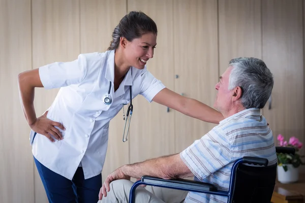 Gelukkig senior man en arts interactie in woonkamer — Stockfoto